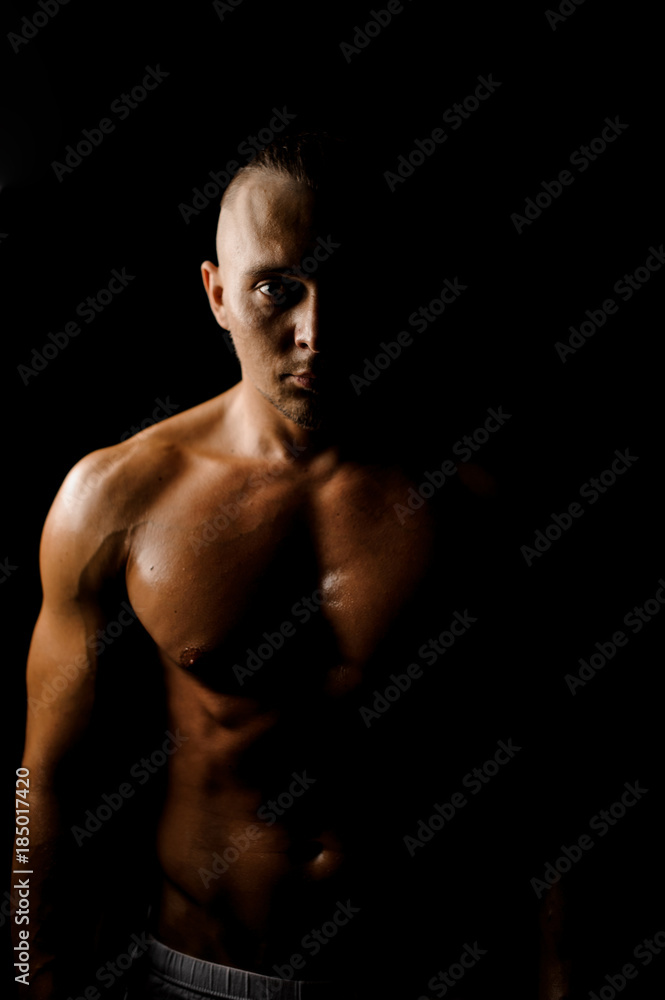Darkened portrait of muscular and tanned young guy