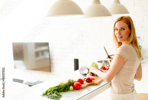Pretty young woman preparing healthy meal in the kitchen