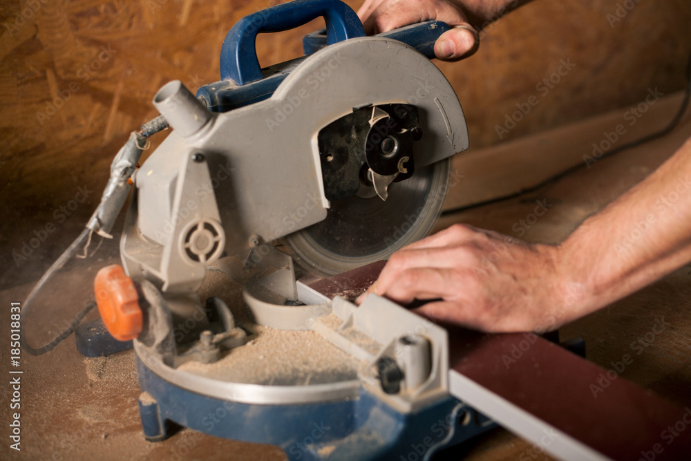 Skilled carpenter cutting a piece of wood in his woodwork workshop, using a circular saw