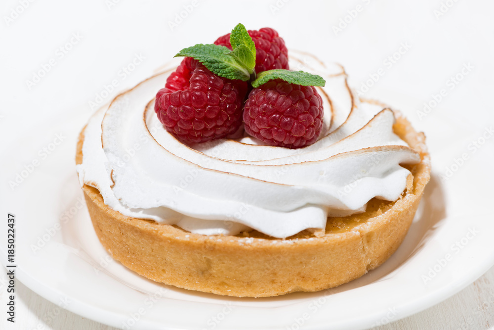 sweet tartlet with meringue and raspberry on white plate sweet tartlet with meringue and raspberry on white plate