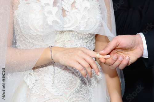 Wedding ceremony.Hand of groom putting a ring on bride's finger.