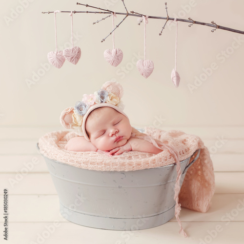 sleeping newborn in the basket, in the bear's cap, valentine's day, pink