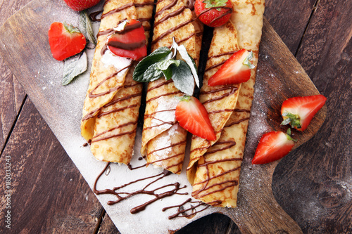 Crepes with jam, berries and sugar powder. Homemade pancakes, delicious breakfast.