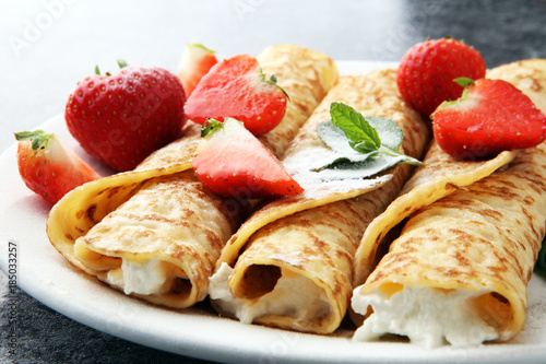 Crepes with jam, berries and sugar powder. Homemade pancakes, delicious breakfast.