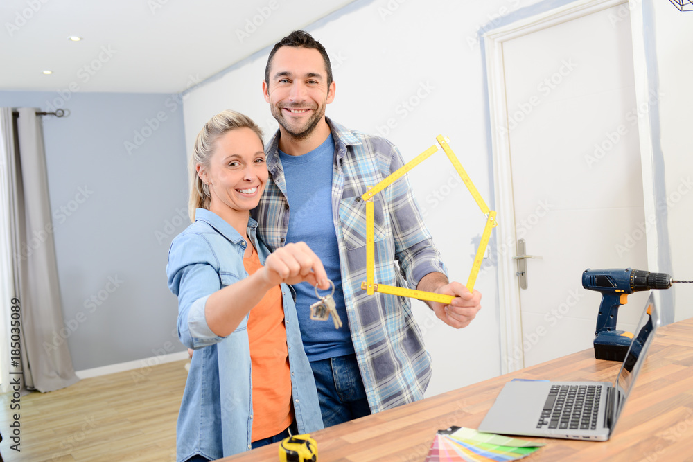 cheerful young couple making future project by renovating their new home and holding their house keys cheerful young couple making future project by renovating their new home and holding their house keys