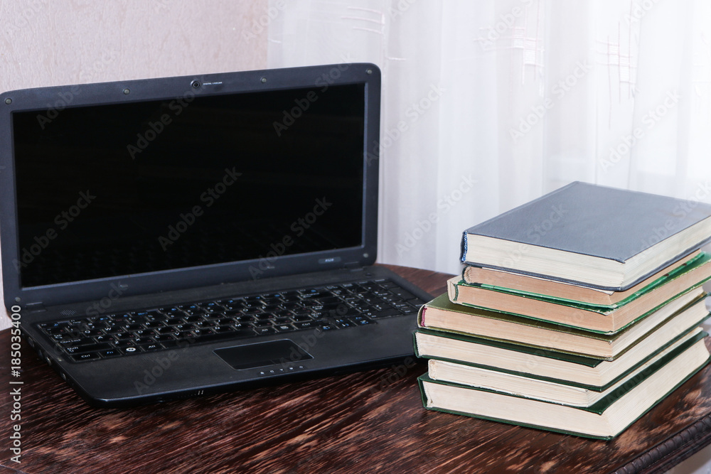 Stack of books and laptop on wooden table Stack of books and laptop on wooden table
