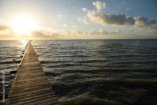 Long wooden pier over water leading to the sunrise and horizon on the Gulf of Mexico photo
