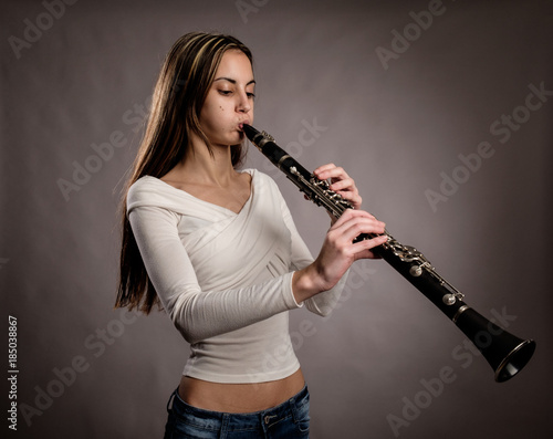 Foto young woman playing a clarinet on a gray background