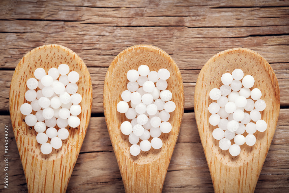 Three woodens spoon of homeopathic globules close up. Homeopathy medicine. Three woodens spoon of homeopathic globules close up. Homeopathy medicine.