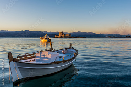 A small wooden boat in Nafplio  Greece with Bourtzi view on the background at sunset