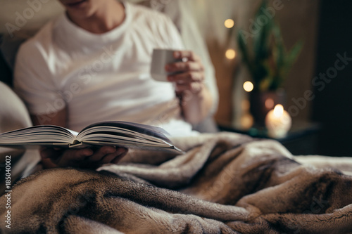Man reading book on bed at home