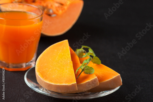 Pumpkin fresh juice in beautiful glasses and jug with pieces of ripe vegetable on brown wooden background. Sweet orange juice. Healthy eating, diet theme. Close up photography. Horizontal banner