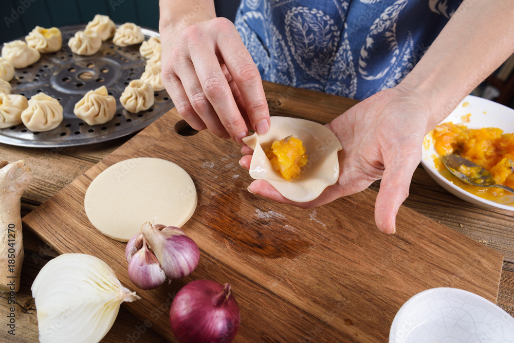 Vegetarian cooking. Woman hands making steam dumplings with pumpkin Vegetarian cooking. Woman hands making steam dumplings with pumpkin