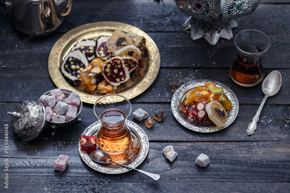Cup of Turkish tea on saucer on rustic wood with snow in front of a dark blurred background with red and golden bokeh lights, copy space, selected focus, narrow depth of field Cup of Turkish tea on saucer on rustic wood with snow in front of a dark blurred background with red and golden bokeh lights, copy space, selected focus, narrow depth of field