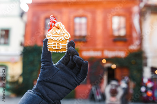 A woman is holding a traditional gingerbread on the background of a Christmas street in the Czech Republic