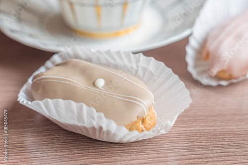 two eclairs on wooden table on cup of tea backhround