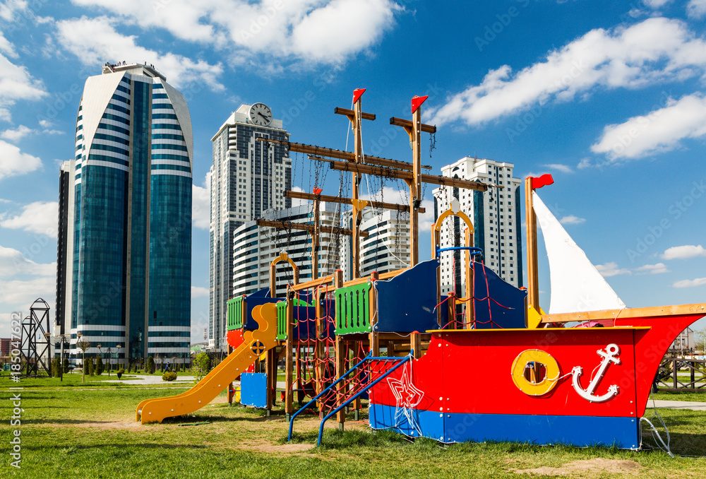 A children's playground in the form of a ship against the background of high-rise buildings in Grozny City.