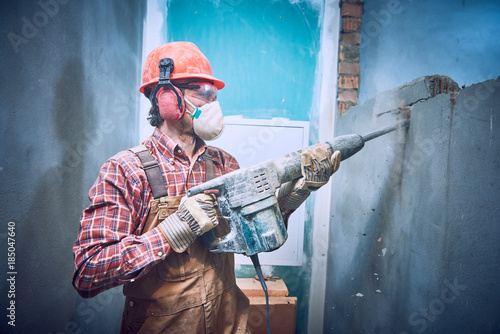 Foto builder with hammer breaking wall indoors