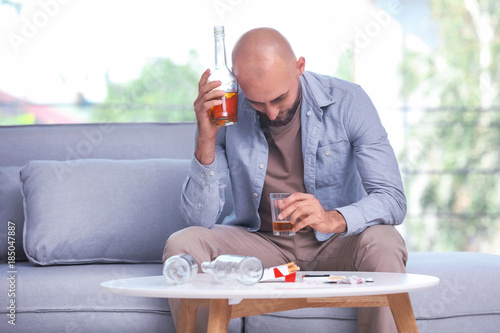 Man drinking whiskey at hom...