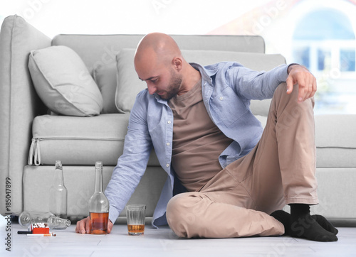Drunk man sitting on floor ...
