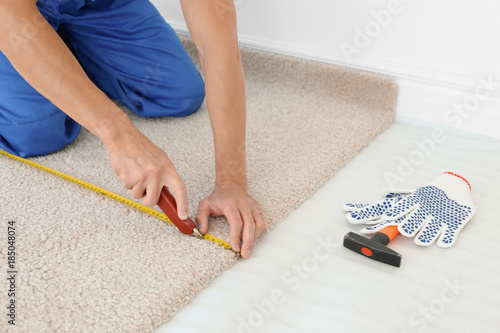Fotografie Worker using cutter while installing new carpet flooring in room