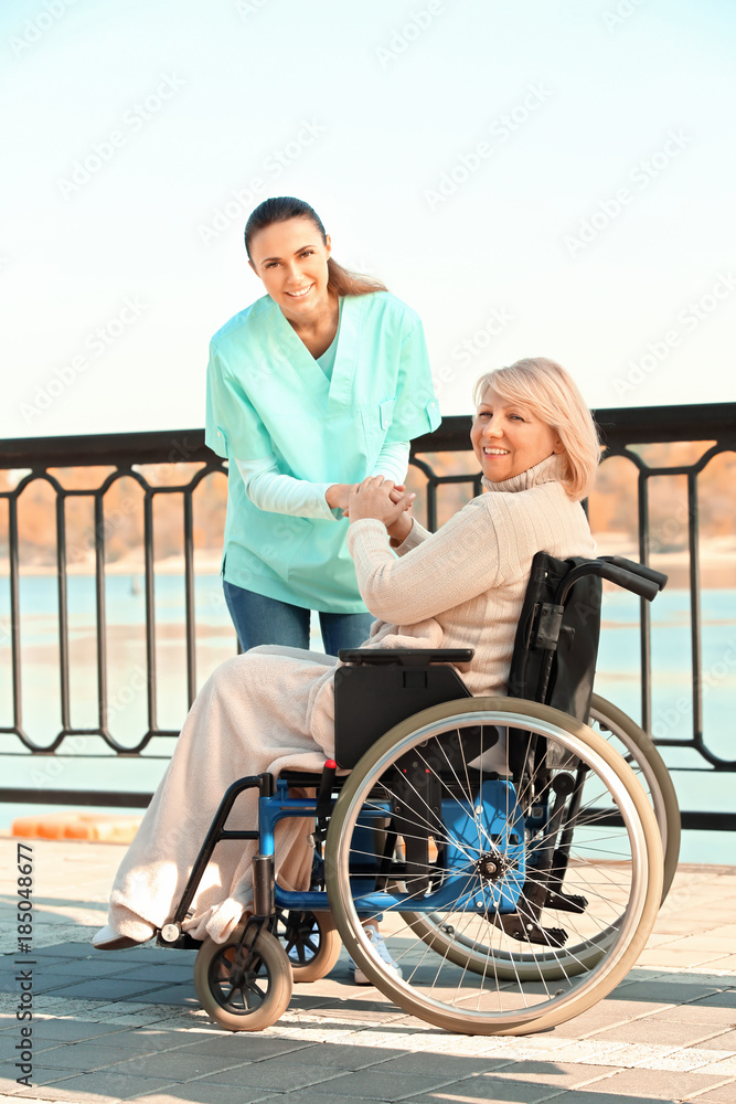 Disabled senior woman and young caregiver outdoors Disabled senior woman and young caregiver outdoors