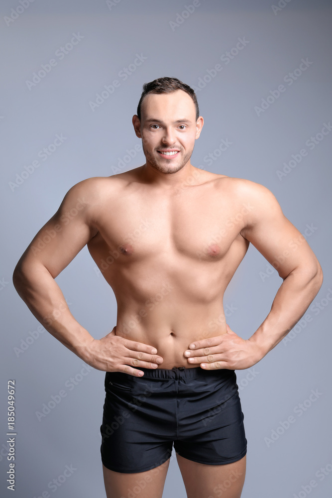 Muscular young bodybuilder on grey background