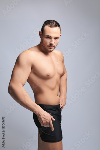 Muscular young bodybuilder on grey background