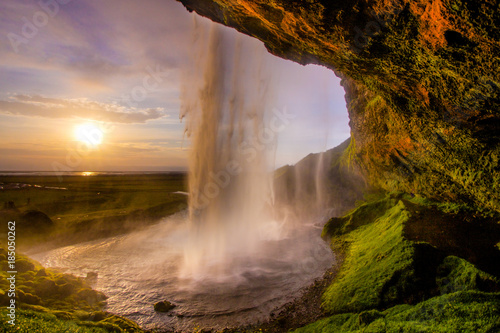 Incredible perspective behind a waterfall during sunset in Iceland. Colorful impression of Seljalandsfoss, Iceland.