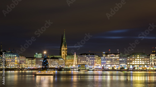 Christmas in Hamburg. Panoramic view of the decorated city center from Alster Lake  view to Hamburg Rathaus and a christmas tree installed in the center of the lake. Atmosphere before the New Year. 