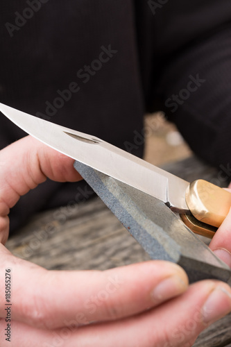 male hands sharpening pin knife.