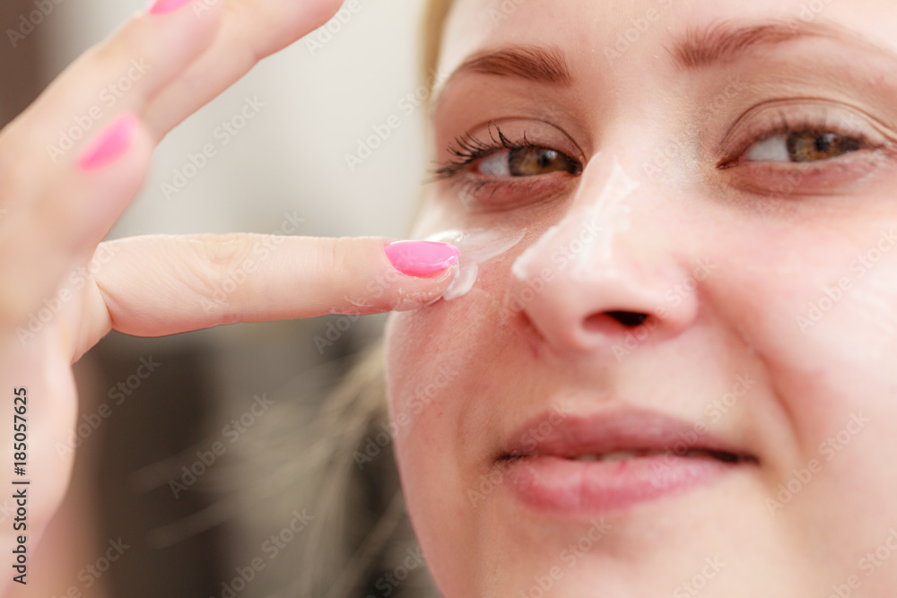 Woman applying face cream with her finger