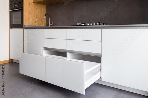 Photos Opened kitchen drawer, kitchen in a modern loft style with wooden elements, grey ceramic countertop and tile backsplash