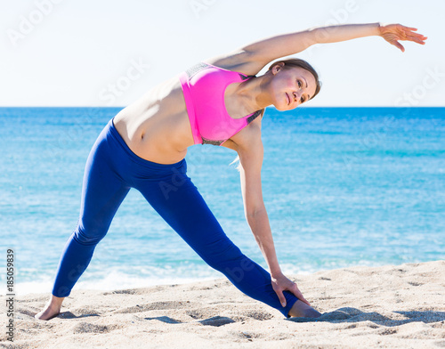 Positive female stretching muscles on the sand