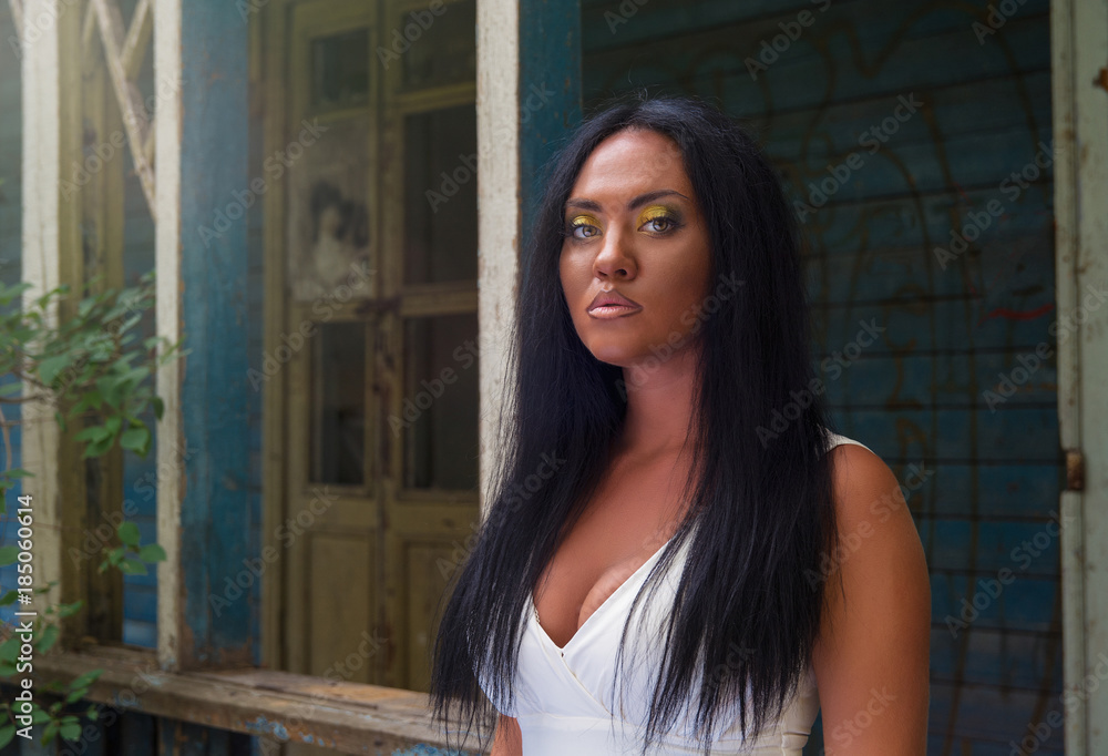 Fototapeta premium Portrait of young black woman against background of an old abandoned house
