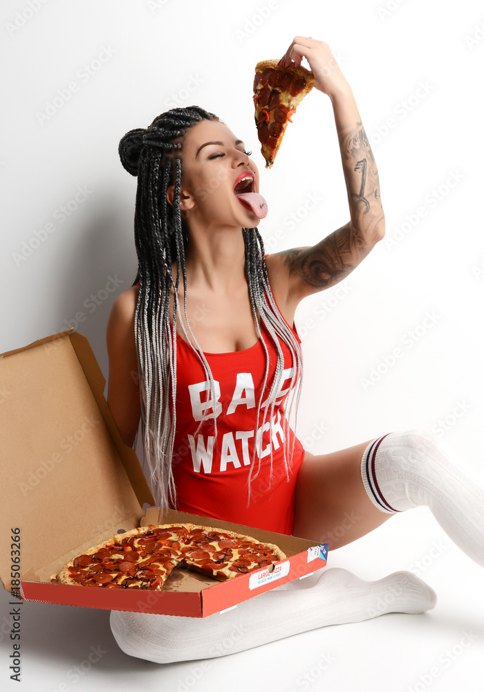 Young beautiful sexy woman in elegant red body vest and dreadlocks eat  pepperoni pizza slice Stock Photo | Adobe Stock