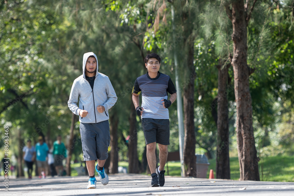 Two young fitness man running at morning in the garden, park