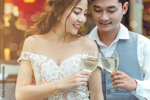Asian man are holding glass of wine and cheer with his girlfriend in restaurant.