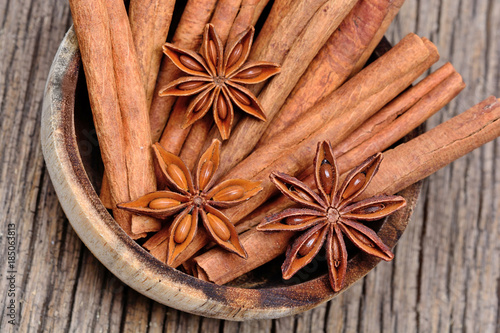 Bowl with cinnamon sticks and anise star on rustic table