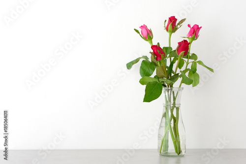 Red and pink roses in glass vase on table and white wall background with copy space  Happy valentine s day concept