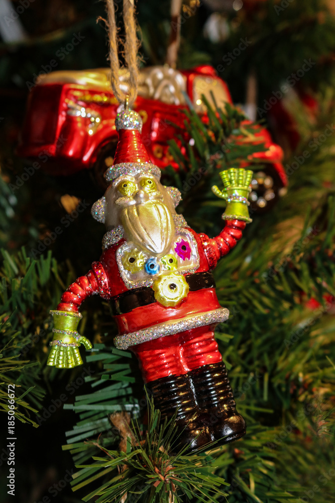 Robot Santa Christmas ornament on green Christmas tree with firetruck ornament in background - selective focus