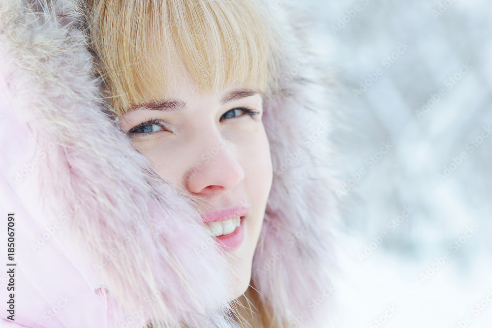 Close up portrait of a beautiful blonde young woman in a winter park
