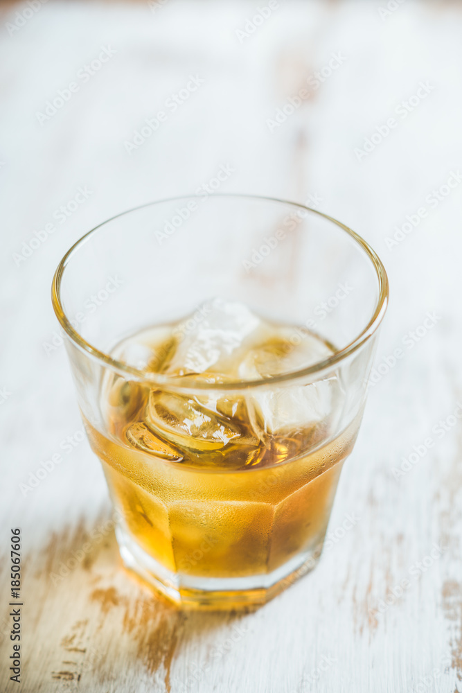 Glass with whiskey on the rustic wooden background. Selective focus. Shallow depth of field.