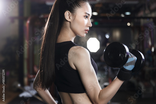 Young woman lifting dumbbell in gym photo