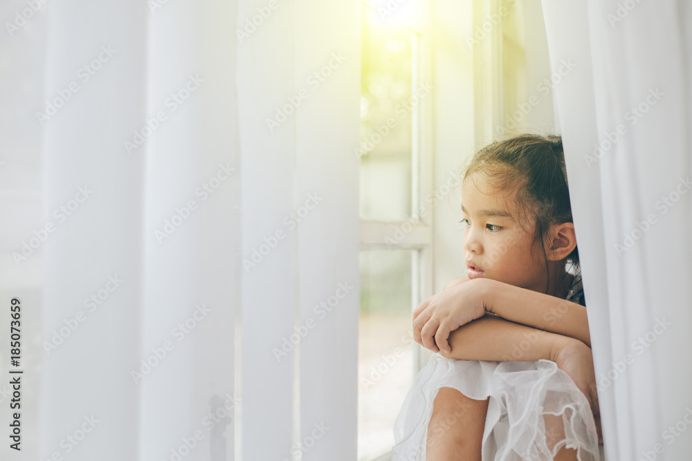 Depressed Little girl near window at home, closeup Depressed Little girl near window at home, closeup