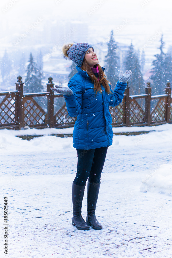 Young cute woman rests on a winter vacation in the mountains, a fun and beautiful winter time. A girl in a snow-covered forest and mountains. Active and joyful outdoor recreation 