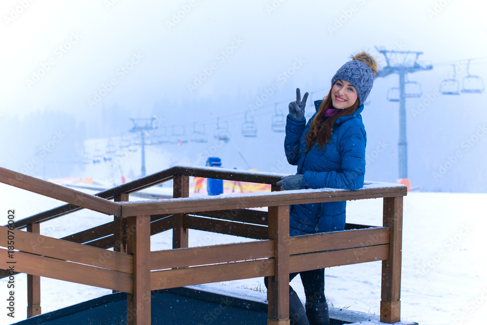 Young cute woman rests on a winter vacation in the mountains, a fun and beautiful winter time. A girl in a snow-covered forest and mountains. Active and joyful outdoor recreation 