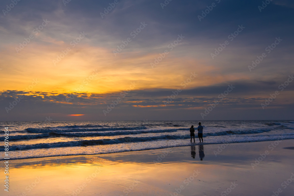 Romantic scene of a couple silhouette of a couple enjoying on the beach watching the sunrise in the morning. Romantic scene of a couple silhouette of a couple enjoying on the beach watching the sunrise in the morning.