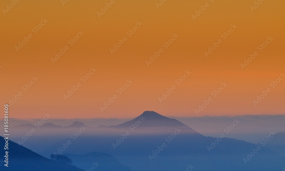 Hill in a fog on a sunrise.