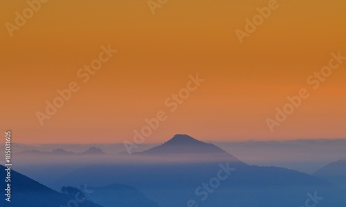 Hill in a fog on a sunrise.